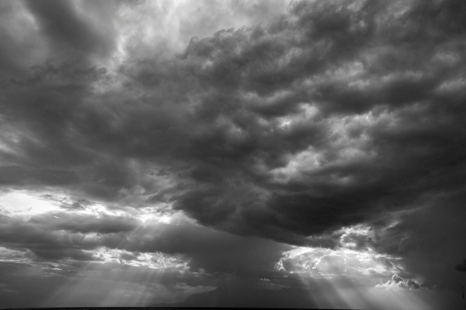 Dark storm clouds gathering in the sky with rays of sunlight breaking through, creating a dramatic and moody landscape. Ideal for weather-related or atmospheric content.