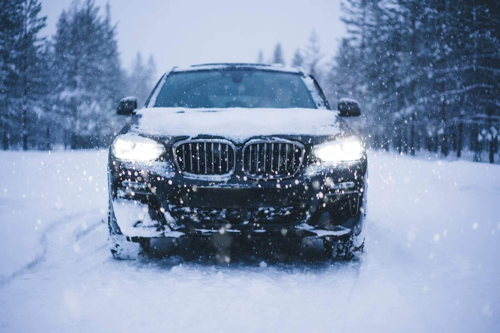 All-wheel drive luxury SUV driving through a snowy landscape with snow falling around, emphasizing winter driving, safety, and performance in cold weather conditions.